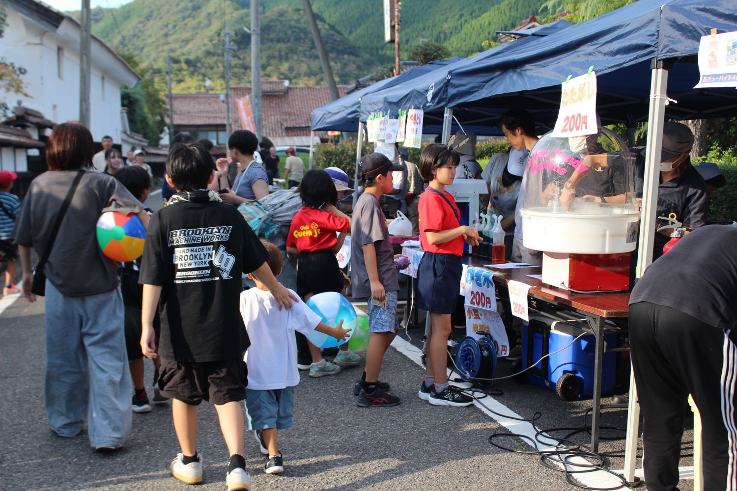 通り沿いに並ぶテントの露店と、順番を待つ子どもたち